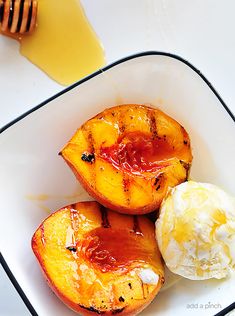 grilled peaches with honey and ice cream in a white bowl on a table