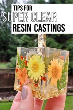 a hand holding up a glass block with flowers in it and the words tips for super clear resin resin castings