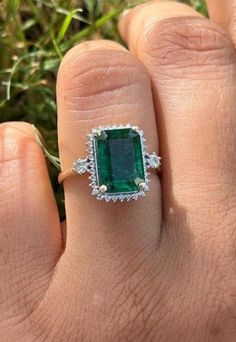 a woman's hand with an emerald and diamond ring on top of her finger