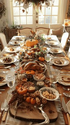 a long table is set with plates, silverware and pumpkins for thanksgiving dinner