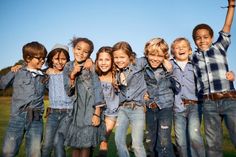 a group of young children standing next to each other on top of a grass covered field