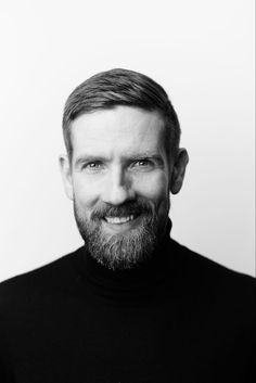 a black and white photo of a man with a goatee smiling at the camera