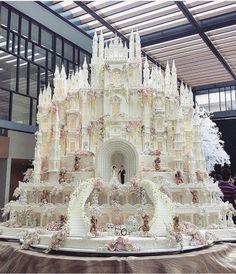 a large white cake with people standing in front of it