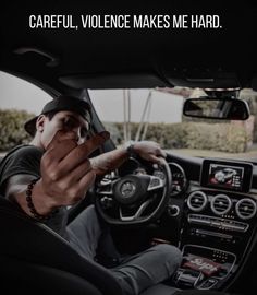 a man sitting in the driver's seat of a car with his hand on the steering wheel