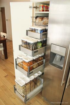 an organized pantry in the corner of a kitchen with stainless steel refrigerator and wooden flooring