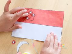 someone cutting out a paper with scissors on a table next to some crafting supplies