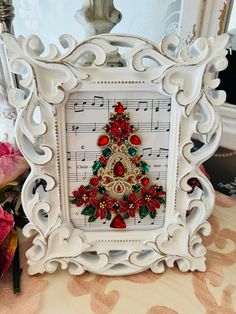 a white frame with a christmas tree on top of music notes and poinsettis