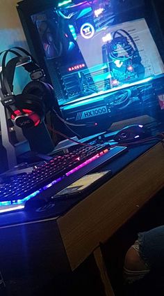 a computer desk with a keyboard, mouse and headphones on it in front of a monitor