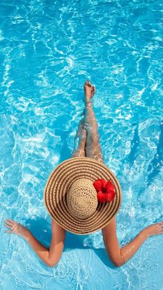 a woman in a straw hat is floating in a pool with her feet up on the edge