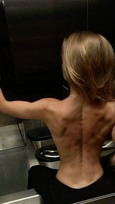 the back of a woman's body is visible in this photo, with no shirt on