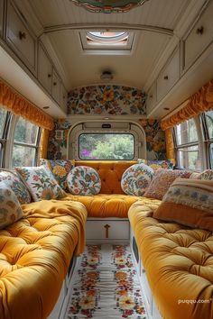 the inside of an rv with yellow couches and floral pillows on each seat area