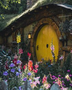 a yellow hobbot door surrounded by flowers and greenery