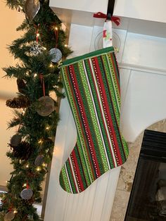 a christmas stocking hanging from a fireplace mantle next to a decorated tree with ornaments on it