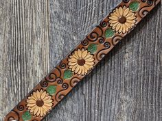 a tie with sunflowers on it is sitting on a wooden table next to a piece of wood