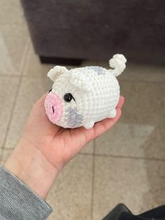 a hand holding a small crocheted pig