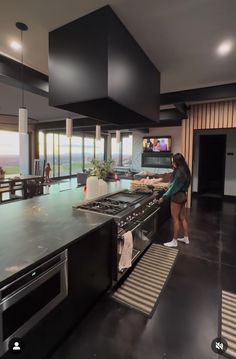 a woman standing in front of an oven inside of a kitchen next to a counter