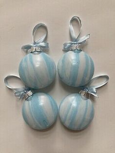 four blue and white striped glass ornaments with bows on them, hanging from the ceiling