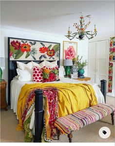 a bed with yellow blankets and colorful pillows