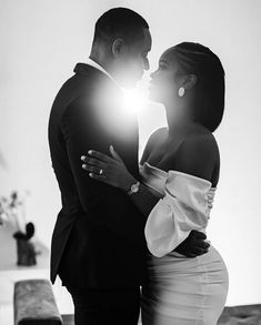 a man and woman standing next to each other in front of a window with the light shining on them