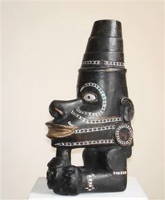 a black sculpture with an eye on it's face and head is sitting on a white pedestal