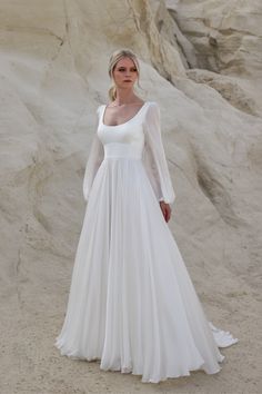 a woman in a white wedding dress standing on the beach