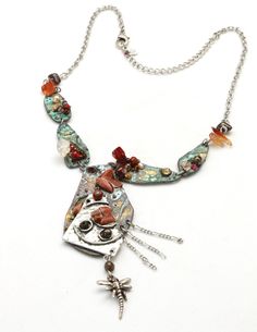 "Artisan Mixed Metals Goldstone Copper Dragon Fly Linked Necklace -Artisan design with copper pieces linked together with a large copper and layered steel pendant piece -Small pieces of goldstone, amber color, clear, and red rock stones are wire wrapped or glued to the copper pieces -Copper pieces are oxidized to show a nice green patina -Dangling from the large pendant piece are 3 matte silver chains and a silver-tone dragonfly charm -Matte silver chain with lobster clasp -Wearable length 14-16 Artistic Silver Copper Necklaces, Artistic Silver Copper Necklace, Artistic Bronze Copper Necklace, Artisan Rust-colored Metal Jewelry, Artistic Copper Jewelry With Soldered Details, Artistic Copper Pendant Necklace, Unique Artistic Copper Jewelry, Silver Amulet Necklace Of Copper, Unique Red Copper Necklace