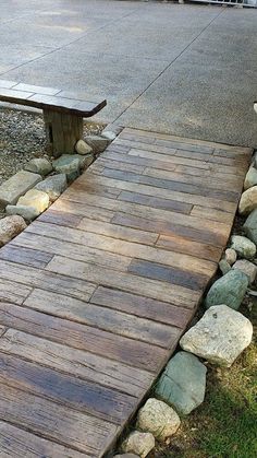 a wooden bench sitting on top of a grass covered field next to a stone path