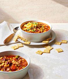 two bowls of soup and crackers on a table