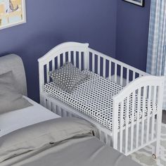 a baby crib in the corner of a room with a blue wall and curtains