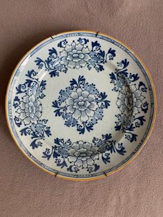 a blue and white plate sitting on top of a brown table next to a wall