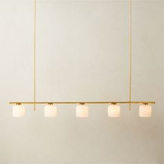 five lights hanging from a gold bar in a room