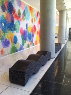 two benches sitting in front of a wall with colorful tiles on it's side