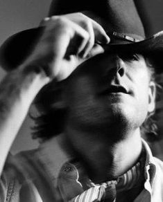 a black and white photo of a man adjusting his hat