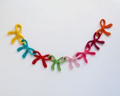 a multicolored crocheted ribbon necklace is displayed on a white surface,