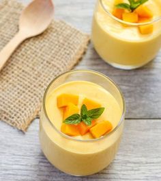 two glasses filled with dessert sitting on top of a wooden table