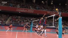 a group of people playing volleyball in front of an arena full of spectators and fans