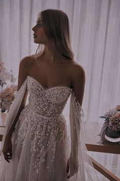 a woman in a wedding dress looking off into the distance