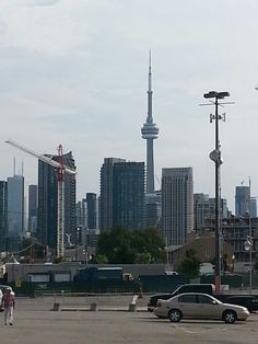 a parking lot with cars parked in front of tall buildings and cranes on the skyline