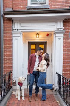 a man and woman standing in front of a door with a dog on a leash