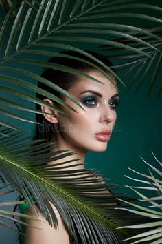 a beautiful woman with makeup and palm leaves