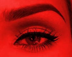 a woman's eye with long lashes and red background