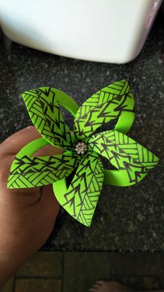 a hand holding a green and black flower on top of a counter next to a sink