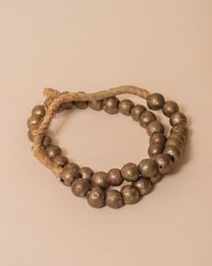 These brass African beads are beautifully textured, each individual bead unique in shape and finish for a final look that feels one-of-a-kind and natural. Perfect for layering on a vase, an open book, a bowl, or styling on a shelf. All Sales Final Free Shipping Artisan Gold Bracelets With Wooden Beads, Bronze Brass Jewelry With Large Beads, Artisan Gold Bracelets With Polished Beads, Gold Artisan Bracelet With Polished Beads, Gold Jewelry With Wooden Beads For Festivals, Bronze Jewelry With Large Beads, Spiritual Gold Jewelry With Wooden Beads, Festival Jewelry With Gold Wooden Beads, Rustic Bronze Beaded Jewelry