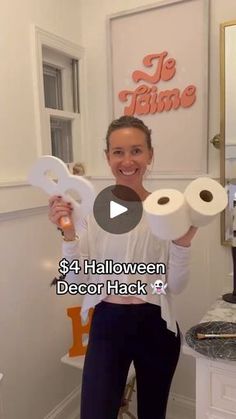 a woman holding two rolls of toilet paper in front of her face with the words $ 4 halloween decor hack