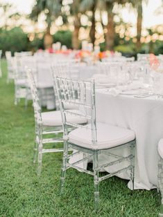 the tables are set with white linens and silver chairs for an outdoor wedding reception