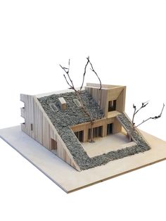 a model of a house with trees and rocks on the roof, in front of a white background