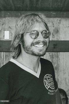 a man with long hair and glasses smiling