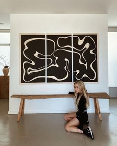 a woman is sitting on the floor in front of two large abstract art pieces,