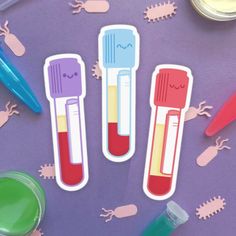 three different colored toothbrushes sitting on top of a purple surface next to other items