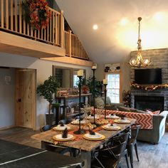 a dining room table is set with plates and place settings in front of the fireplace